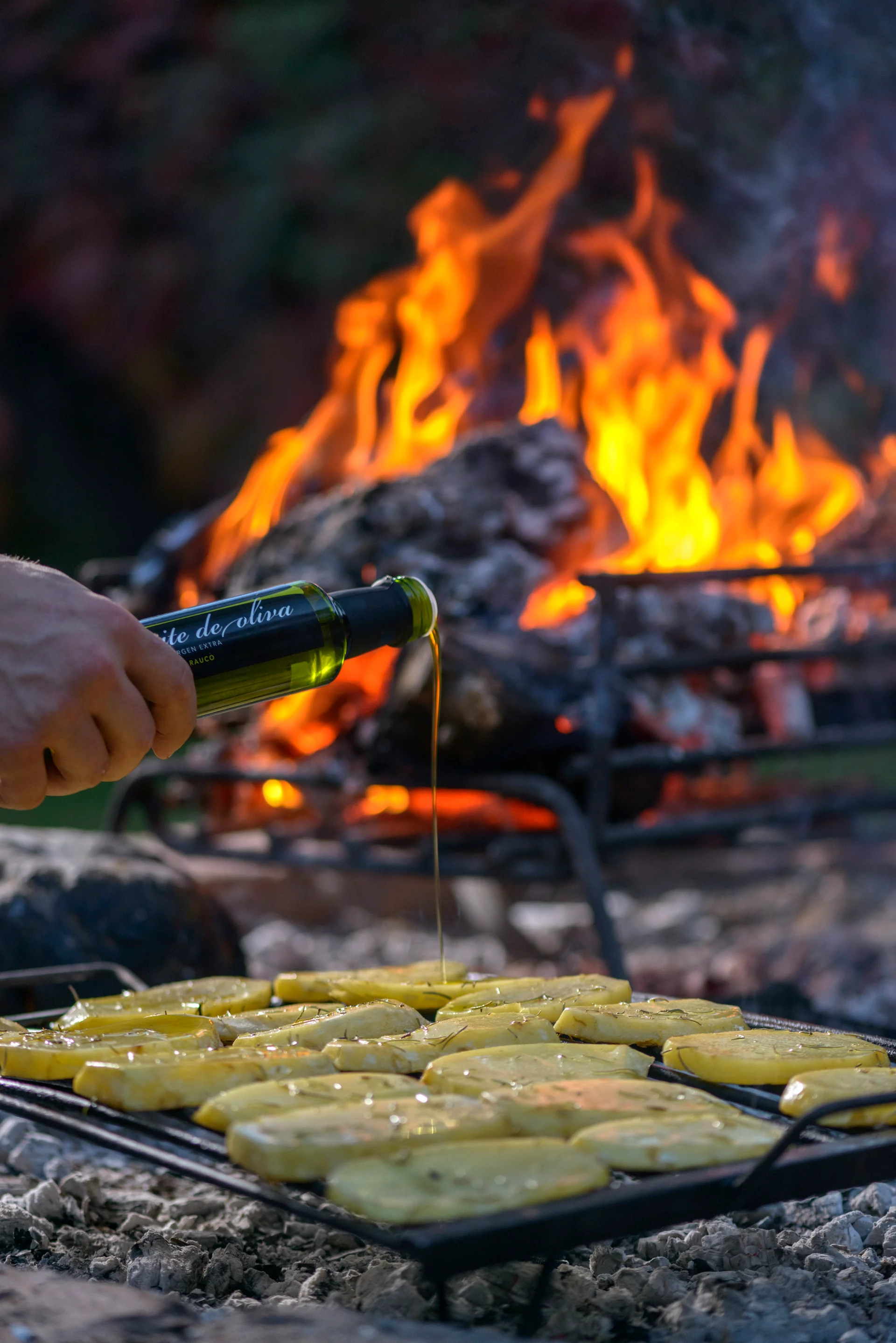 Aceite de oliva de la finca sobre las papas en las brasas